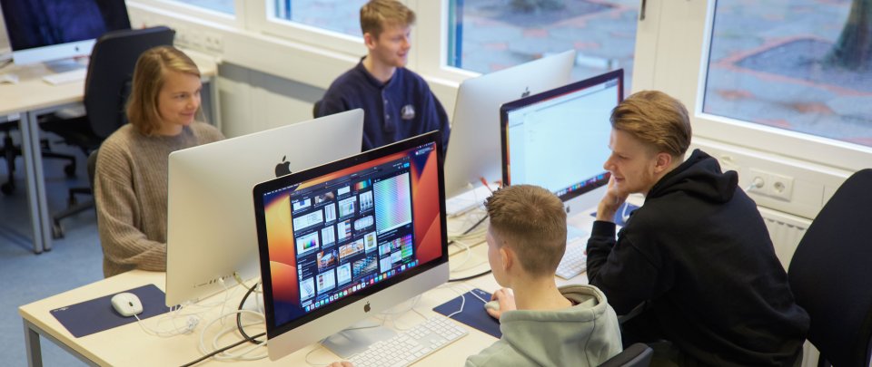 Vier Studierende arbeiten an einer Arbeitsinsel an ihren Computern.